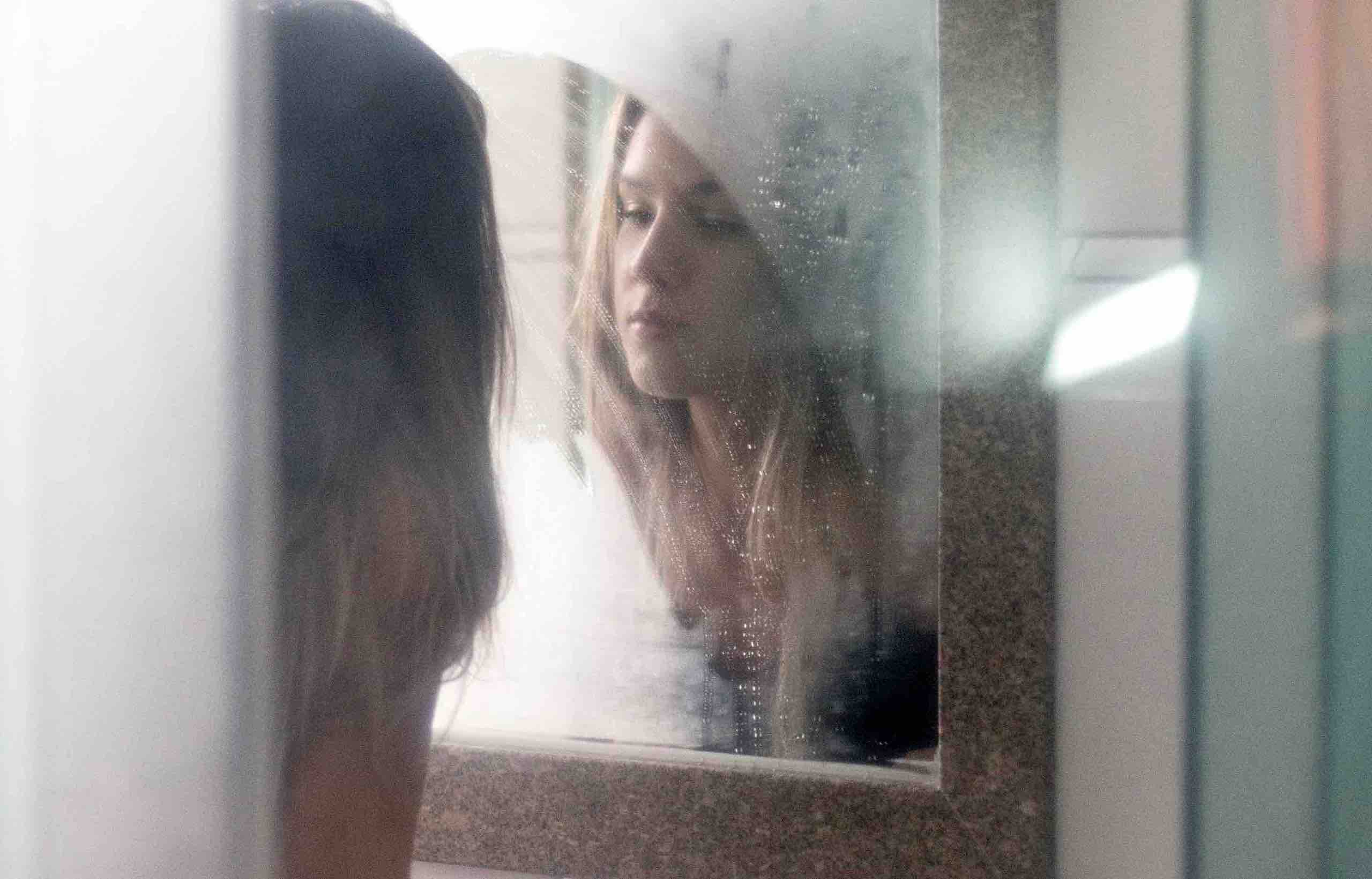 Frau schaut in beschlagenen Spiegel