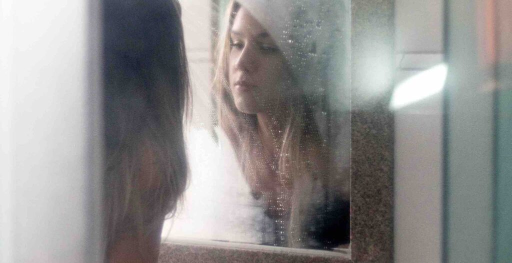 Frau betrachtet sich im Spiegel